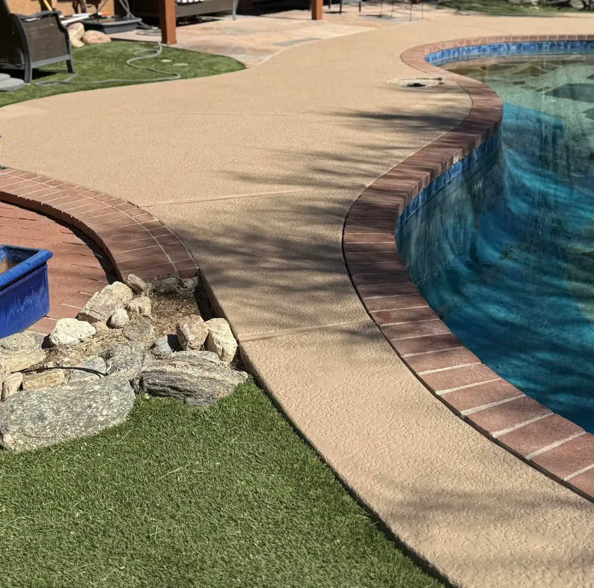 Resurfaced pool deck beside a clear pool after work by Blue Dolphin Pools
