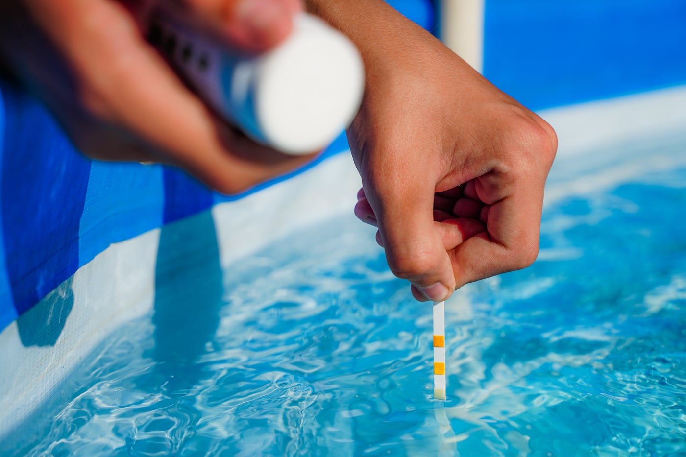 Testing pool water with a test strip beside a Tucson pool