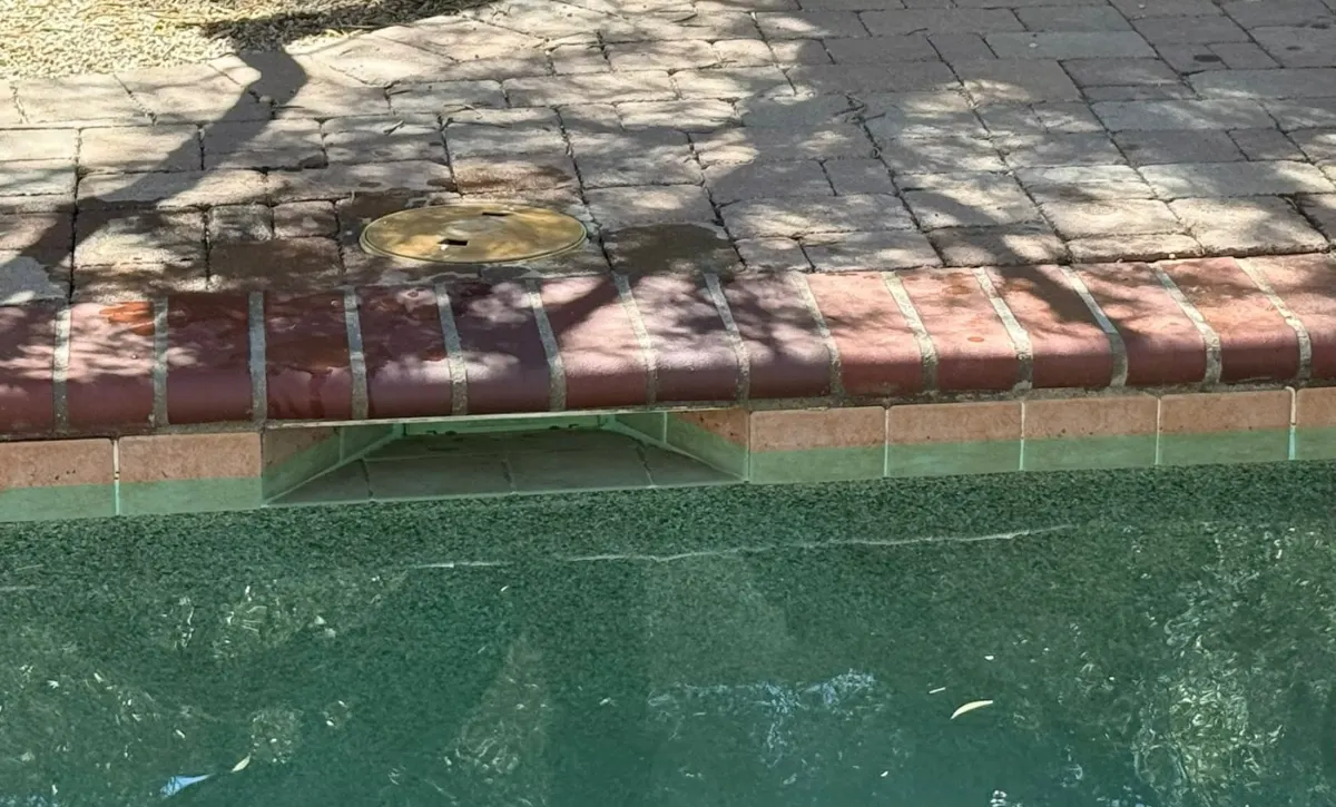 Spa spillway edge with calcium scale before tile cleaning in Tucson